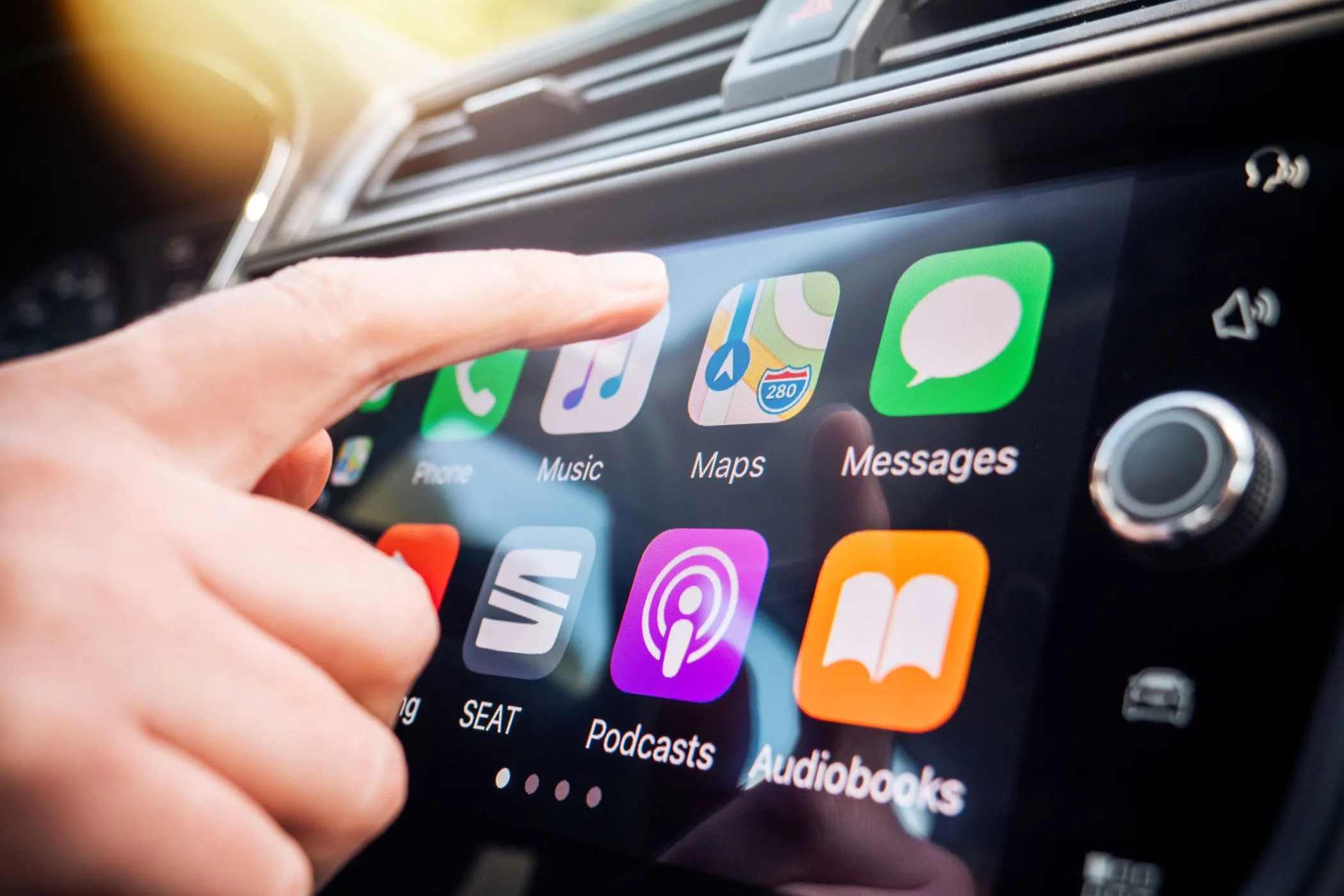 Người dùng tương tác với Apple CarPlay trên màn hình cảm ứng của xe hơi, thể hiện trải nghiệm kết nối thông minh.