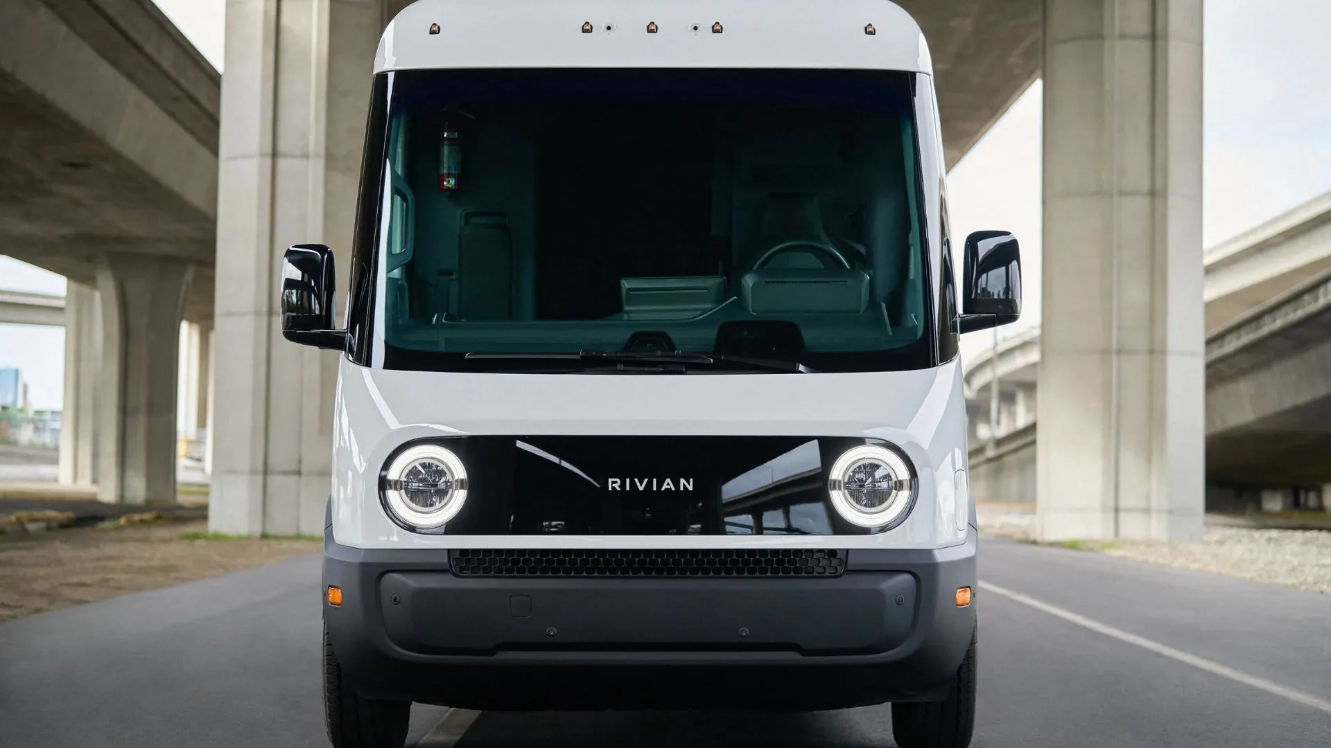 Xe van điện Rivian màu trắng đang di chuyển trên đường, biểu thị việc Rivian mở rộng đối tượng khách hàng ngoài Amazon