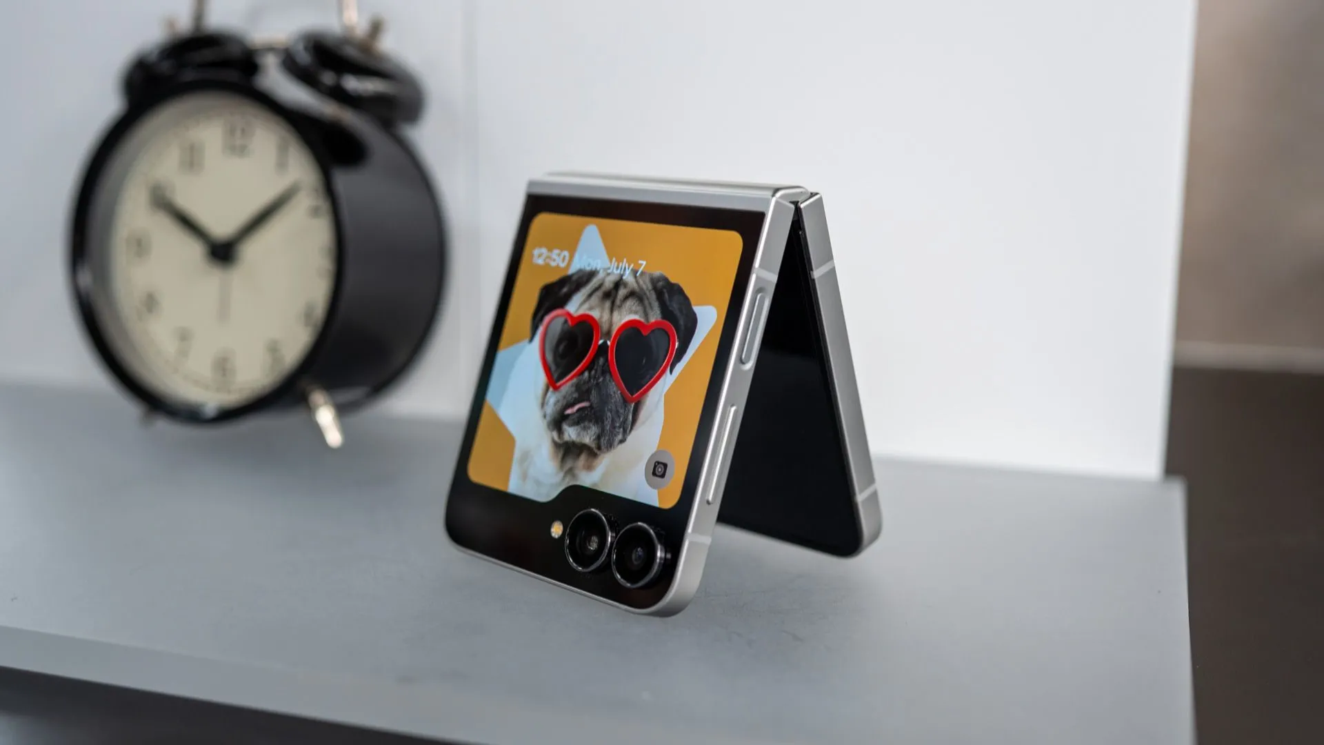 Điện thoại gập Samsung Galaxy Z Flip 7 FE màu đen đặt trên bàn, màn hình phụ đang hiển thị, làm nổi bật thiết kế thanh lịch và màn hình ngoài của dòng điện thoại gập Samsung