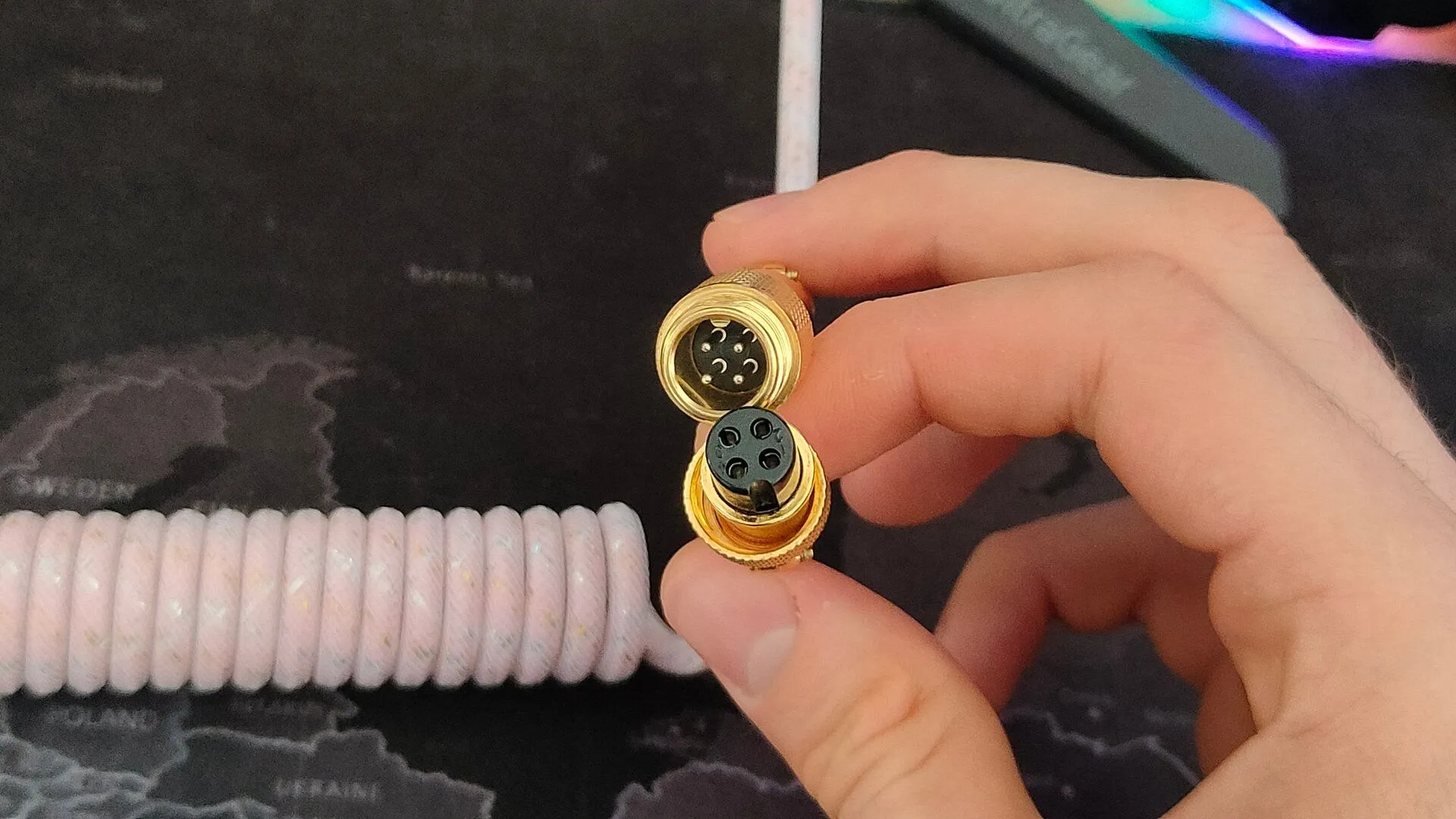 Hai mặt của một đầu nối aviator màu vàng cho cáp bàn phím, thể hiện cấu trúc kết nối tách rời.