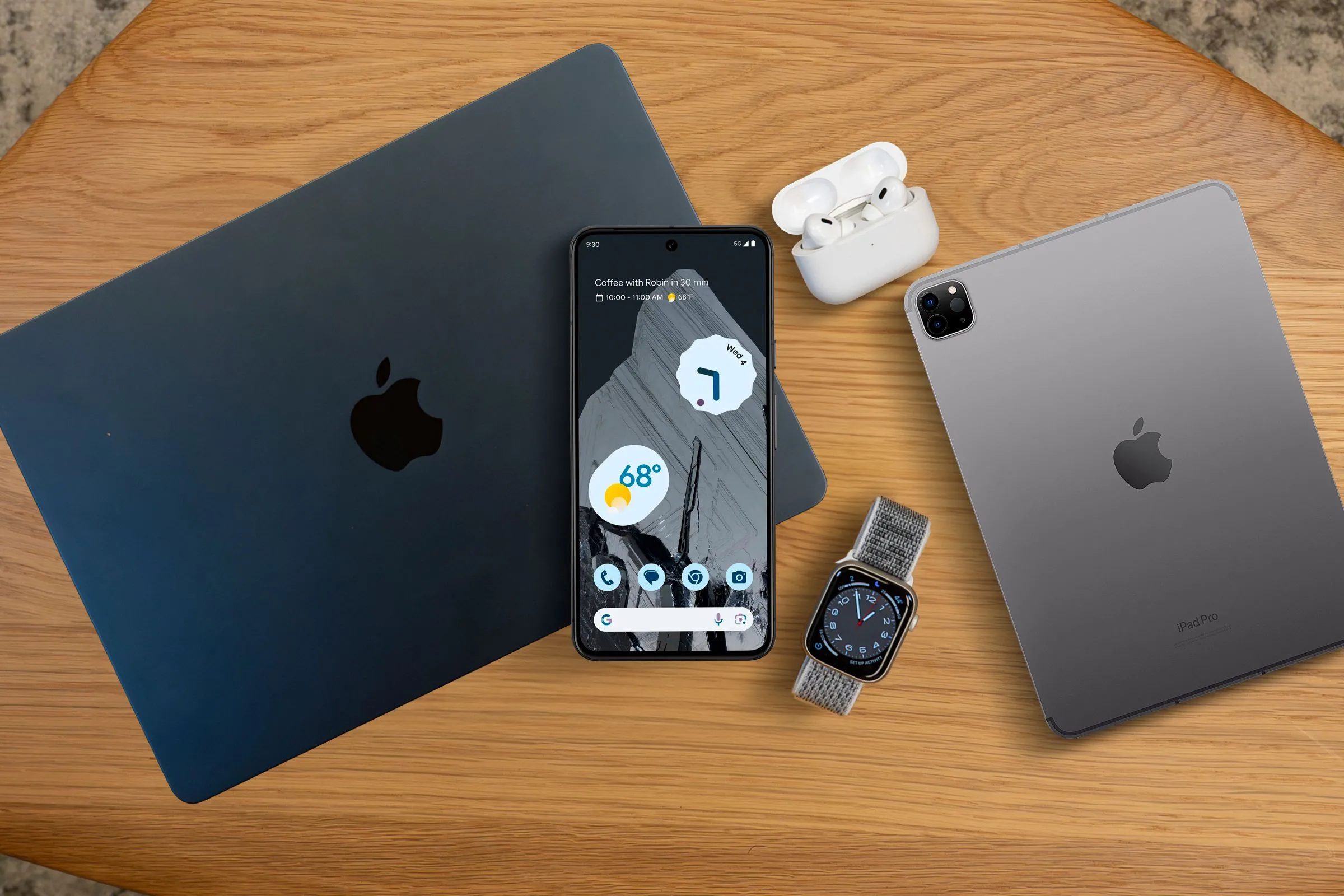Hệ sinh thái thiết bị công nghệ gồm MacBook, iPad, Apple Watch, AirPods và điện thoại Android, minh họa khả năng tương thích đa nền tảng