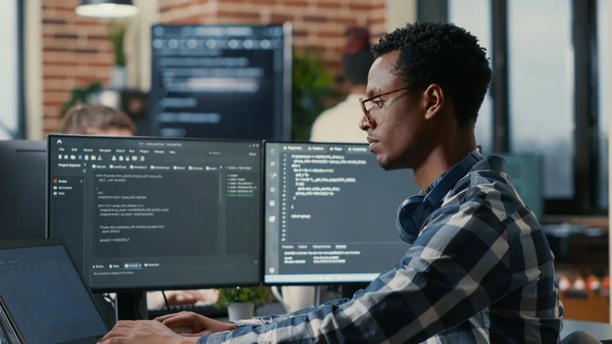 Lập trình viên làm việc hiệu quả với laptop và nhiều màn hình, minh họa khả năng điều hướng và quản lý đa thiết bị bằng Remote Desktop