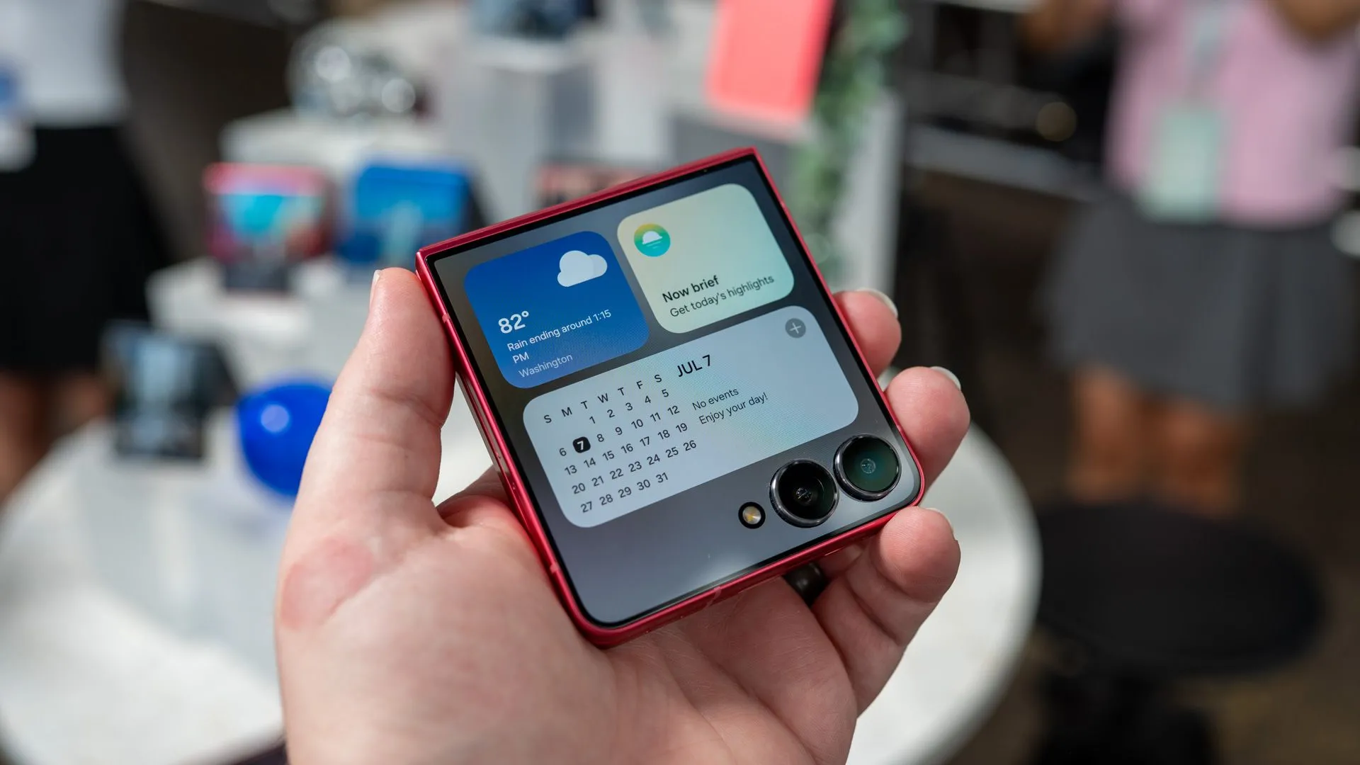 Một người đang cầm chiếc Samsung Galaxy Z Flip 7 FE đã gập, hiển thị các widget trên màn hình phụ, cho thấy khả năng tương tác của màn hình ngoài điện thoại gập