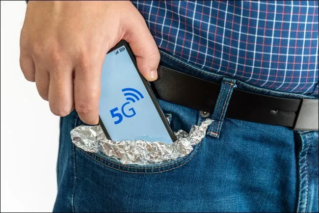 Người đàn ông đặt điện thoại 5G đã bọc giấy bạc vào túi để chống hack hoặc tín hiệu 5G.