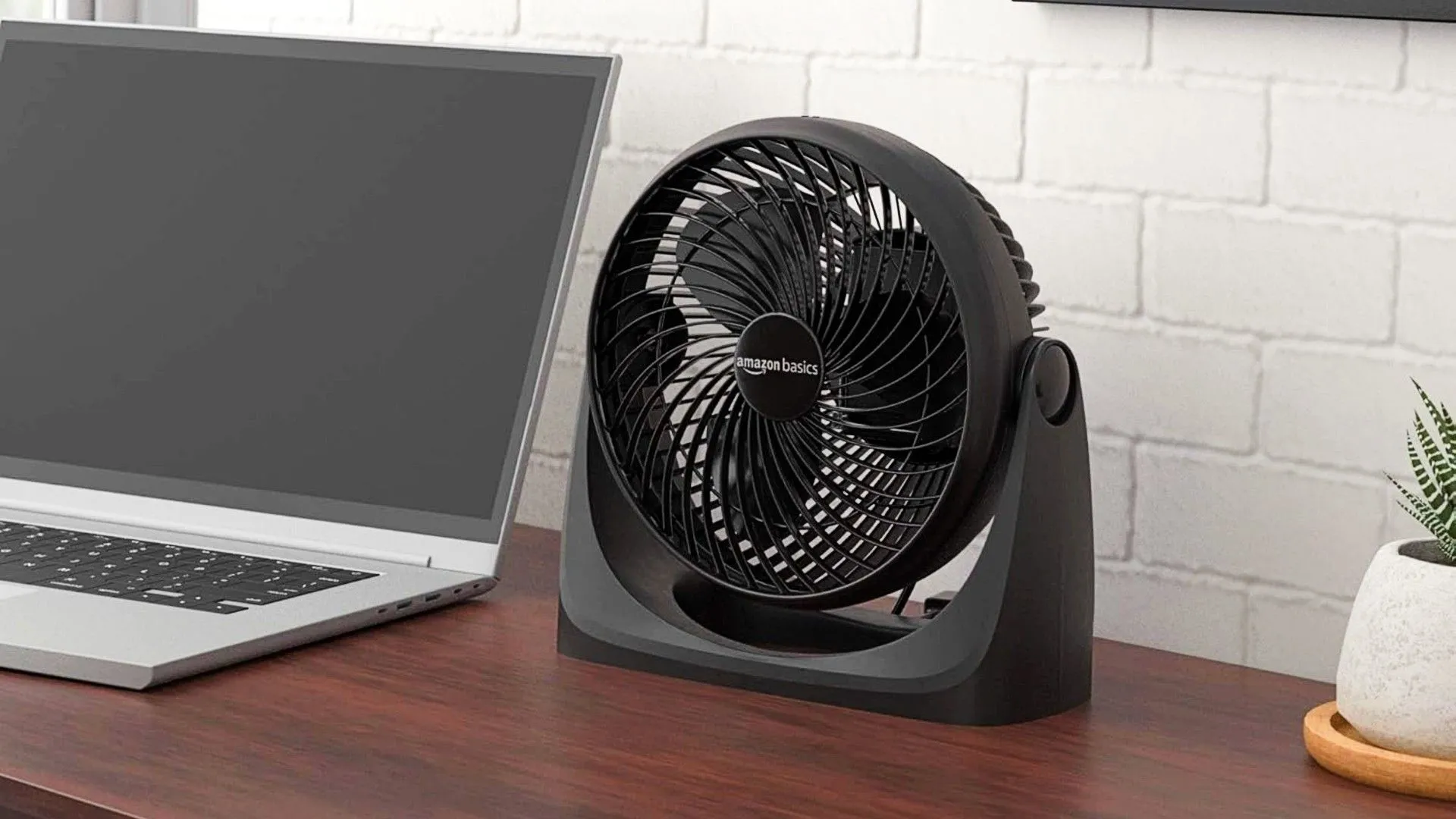 Quạt bàn Amazon Basics đặt trên bàn làm việc cạnh laptop, giúp duy trì không khí mát mẻ và sự tập trung khi làm việc tại nhà.